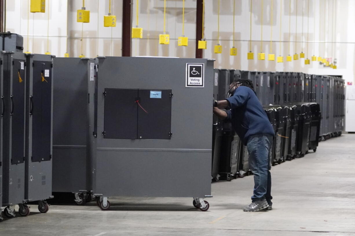 FILE - A worker returns voting machines to storage at the Fulton County Election preparation Center on Nov. 4, 2020 in Atlanta, Ga. The list of security breaches at local election offices since the 2020 election keeps growing, with investigations ongoing in at least three states, Colorado, Georgia and Michigan. Security experts say the breaches by themselves have not necessarily increased threats to the November elections, but say they increase the possibility that rogue election workers could access election equipment to launch attacks.