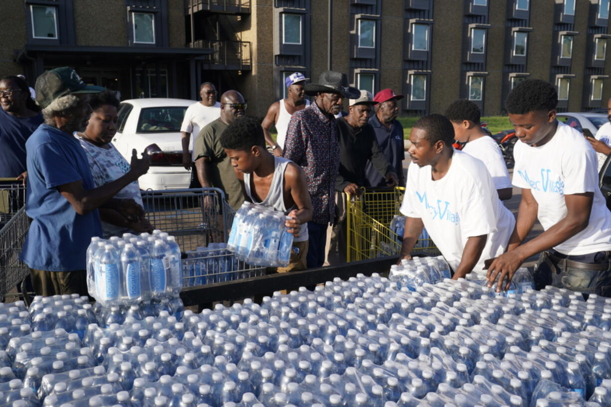 Residents of the Golden Keys Senior Living apartments flock to a trailer full of water being delivered by the AIDS Healthcare Foundation in Jackson, Miss., Thursday, Sept. 1, 2022. A recent flood worsened Jackson's long standing water system problems.