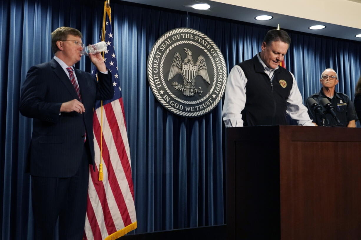 Mississippi Emergency Management Agency executive director Stephen C. McCraney, center, speaks about the coordinated response of federal, state, city and neighboring states agencies, to help Jackson, Miss., deal with its long-standing water problems, while Gov. Tate Reeves, takes a drink of water, at a Thursday, Sept. 15, 2022, news conference during which time, Reeves announced the state imposed boil-water notice has been lifted in Mississippi's capital city after nearly seven weeks. (AP Photo/Rogelio V.