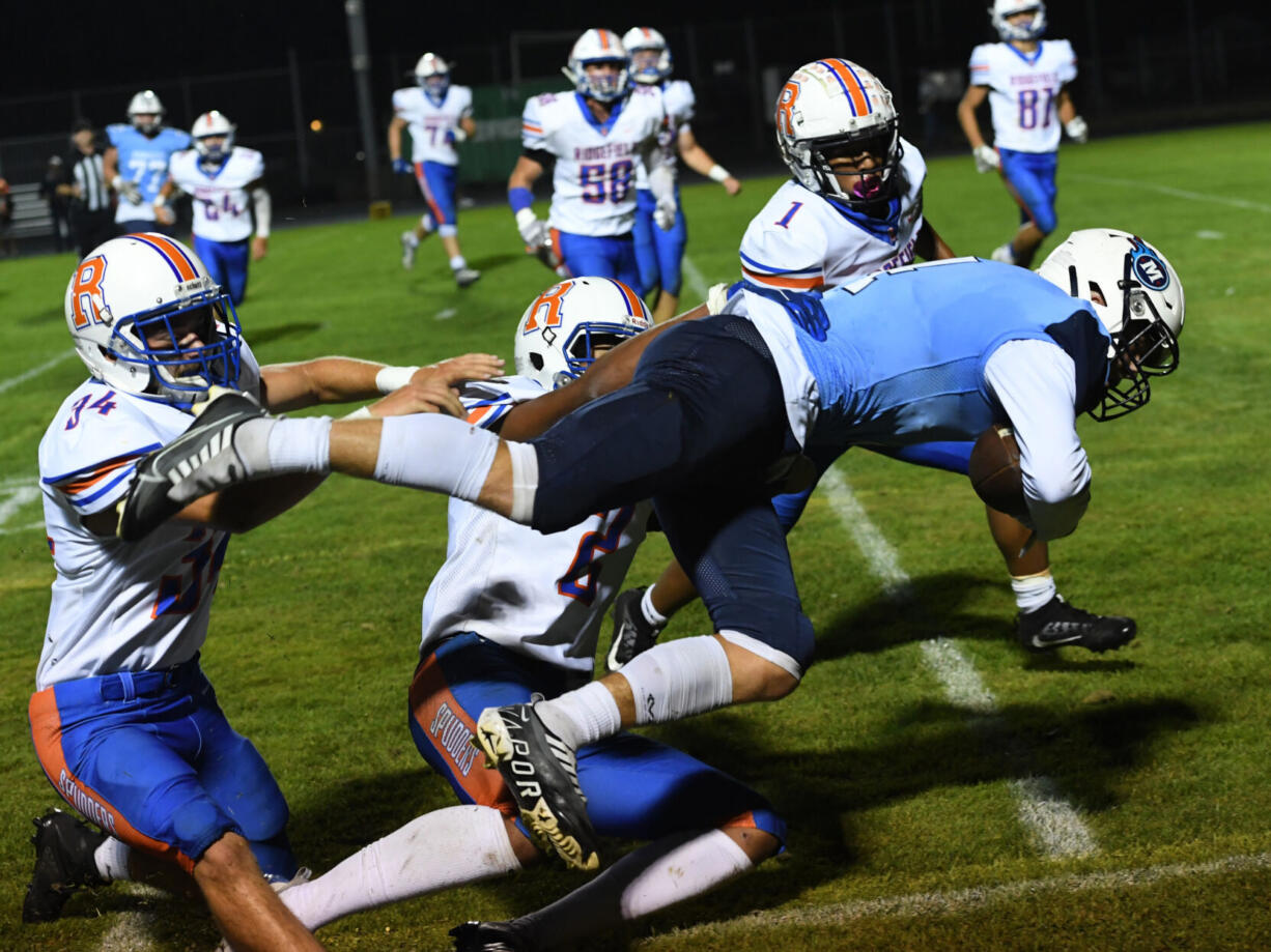 Mark Morris’ Deacon Dietz is brought down by a trio of Ridgefield defenders during the Monarchs’ 20-7 win over Ridgefield on Friday, Oct. 7, 2022.