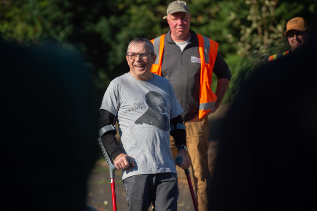 Paul Danzer, a longtime local sports reporter, listens as colleagues and friends extol his virtues during a tree-planting ceremony dedicated to him at Biddlewood Park in Vancouver.