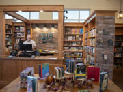 Paul Warnock, co-owner of Copper Bell Bookshop in Ridgefield, works behind the front counter of the newly opened shop. The store opened Oct. 1.  At top, pedestrians stroll past the nearly 1,400-square-foot space that is home to new books.