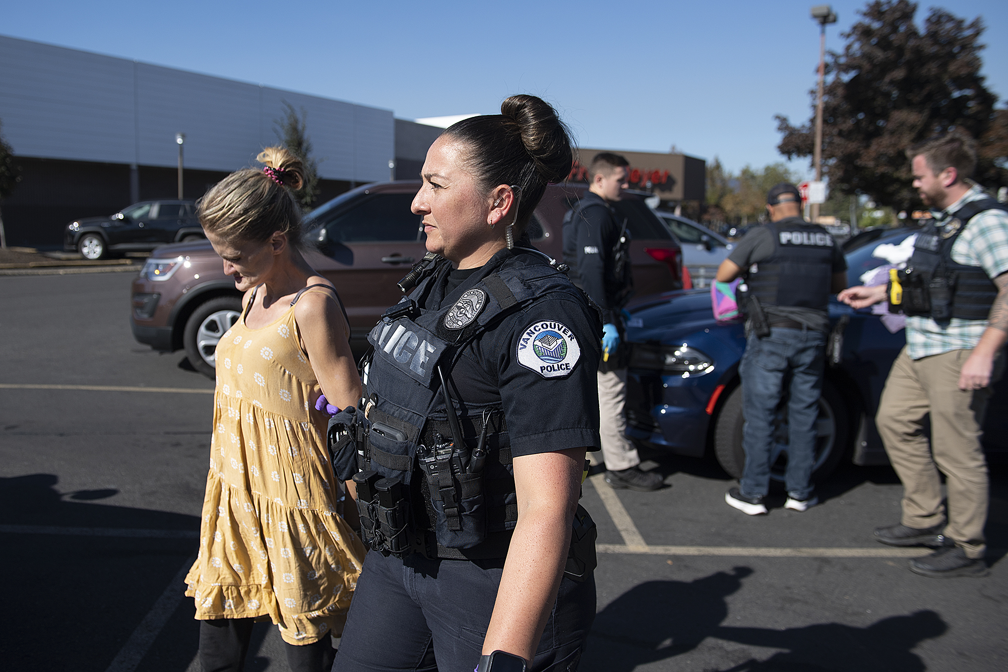 Officer Andrea Mendoza of the Vancouver Police Department escorts a suspected shoplifter into a patrol car at the Fred Meyer store in Cascade Park on Wednesday afternoon, Oct. 12, 2022. The woman was booked and released later in the afternoon. The agency says this is a growing problem and has begun patrol shifts emphasizing on retail theft.