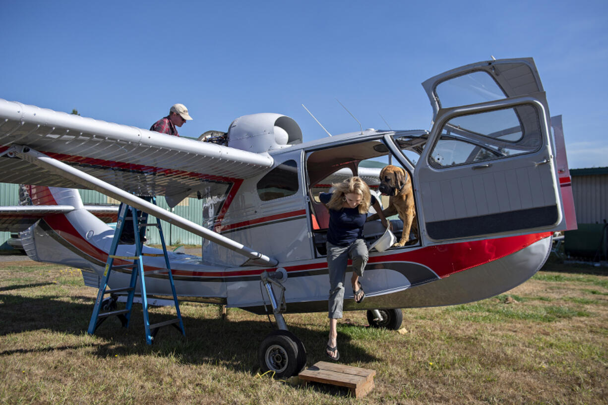 Jay Bell, left, aircraft-restoration specialist for the Western Antique Aeroplane & Automobile Museum, works on a 1947 Republic RC-3 Seabee as Sally Runyan hops out of the aircraft with her dog, Luke, at Green Mountain Airport on Oct. 11. Runyan donated the aircraft to the museum in Hood River, Ore. She has gradually been letting go of planes restored by her late husband, Ben Runyan, who died in a 2008 plane crash.