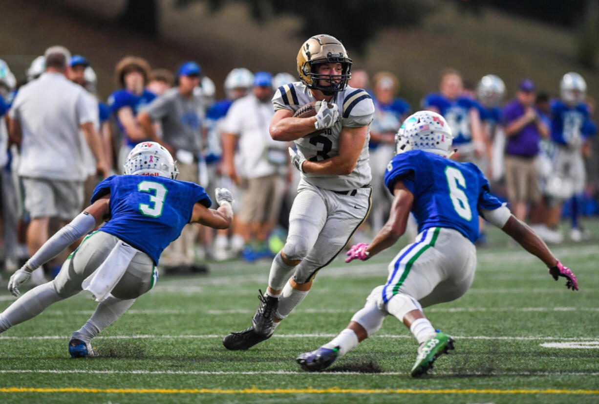 Kelso senior Conner Noah, center, smirks as he jukes two Mountain View defenders on Thursday, Oct. 13, 2022, during the Hilanders??? 28-26 win against Mountain View at McKenzie Stadium.