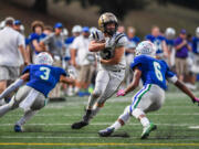 Kelso senior Conner Noah, center, smirks as he jukes two Mountain View defenders on Thursday, Oct. 13, 2022, during the Hilanders??? 28-26 win against Mountain View at McKenzie Stadium.