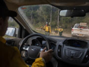 Marcus Kauffman of the Oregon Department of Forestry, left, passes fire crews as they work at the Nakia Fire on Wednesday afternoon, Oct. 19, 2022.