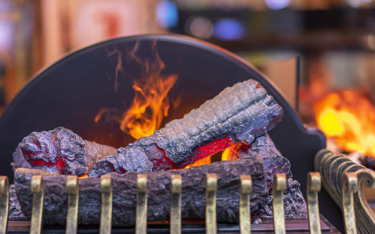 You can use imitation logs and brass furnishings to enhance the look of an electric fireplace "flame." (Dreamstime)