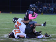 R.A. Long running back TraMayne Jenkins (21) is taken down by Washougal defender William Cooper (24) during the 2A Greater St. Helens League game Friday at Longview Memorial Stadium.