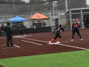 Union's Makenna Johnson hits the ball as Sophia Richard (6) takes off from first base and Battle Ground Makenzy Newton (26) looks on during the 4A district slowpitch softball playoff at Heritage High School on Friday, Oct. 21, 2022.