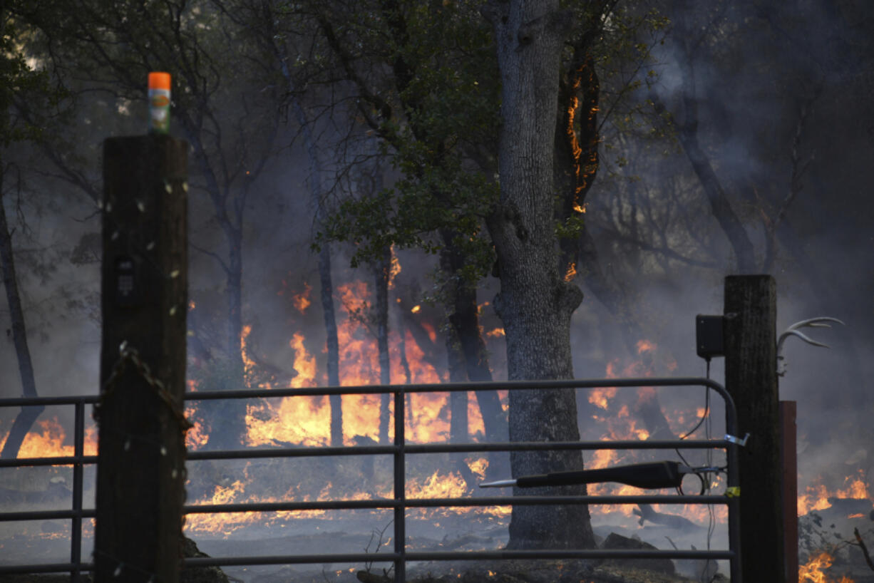 Flames from the Rices Fire burn near a home along Troost Trail Tuesday, June 28, 2022, in rural North San Juan, Calif.