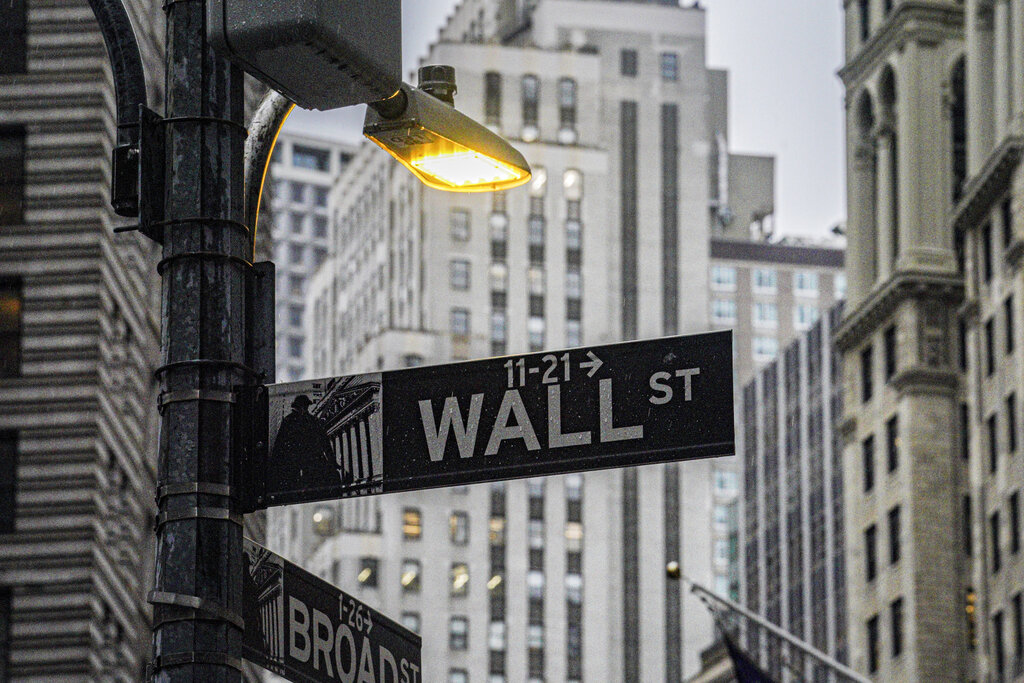 FILE - A street light brightens a Wall Street sign outside the New York Stock Exchange, Oct. 3, 2022, in New York. Stocks wavered between gains and losses in early trading on Wall Street, leaving indexes mixed as another batch of companies reported their latest quarterly results. Several companies including Netflix and United Airlines rose sharply while others, including Abbott Laboratories and M&amp;T Bank, sank. The S&amp;P 500 shook off an early slump and was little changed after the first half-hour of trading Wednesday, Oct. 19, 2022.