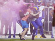 A protester is hit by Los Angeles Rams defensive end Takkarist McKinley, middle left, and linebacker Bobby Wagner during the first half of an NFL football game between the San Francisco 49ers and the Rams in Santa Clara, Calif., Monday, Oct. 3, 2022. (AP Photo/Godofredo A.