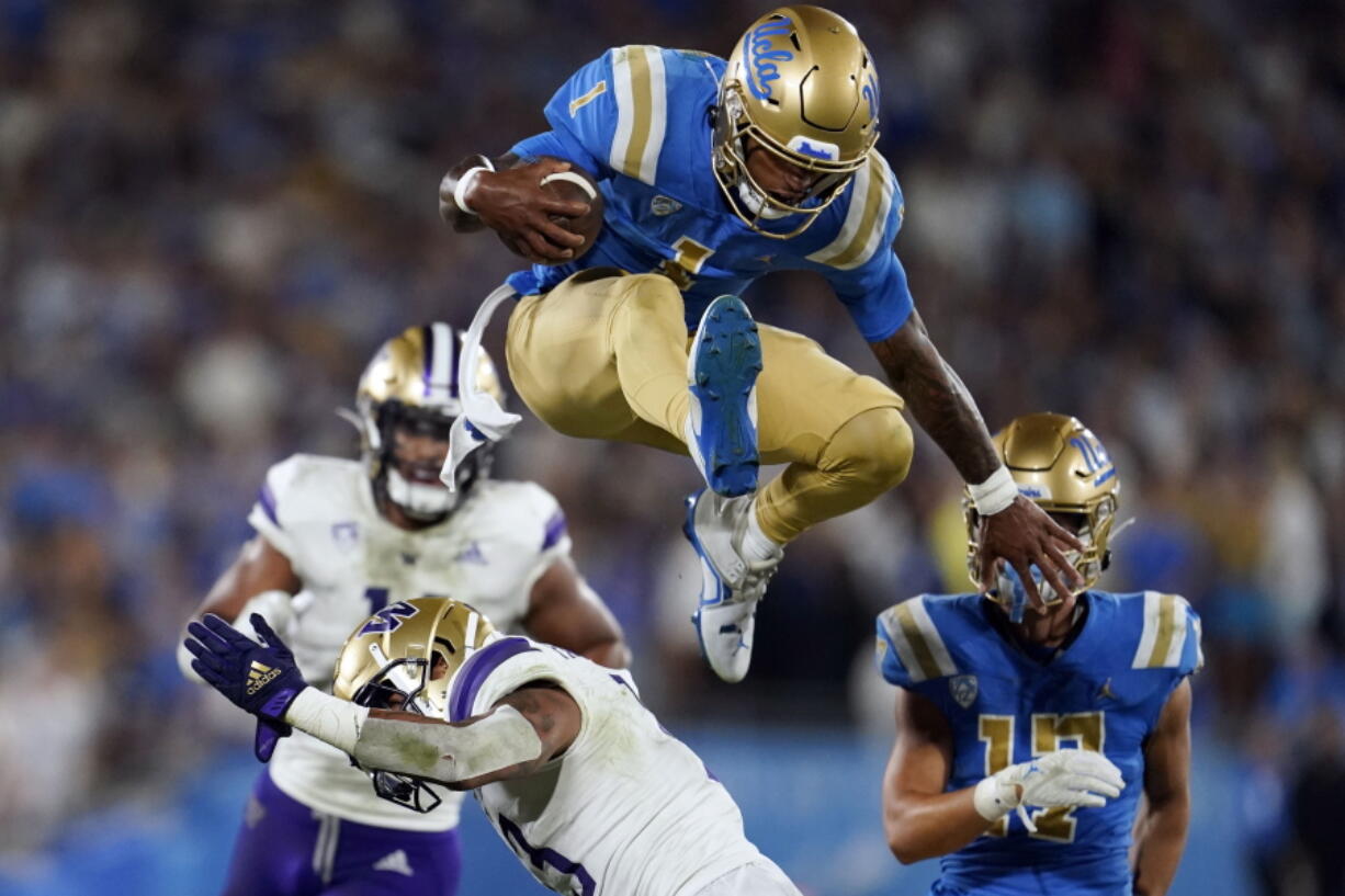 UCLA quarterback Dorian Thompson-Robinson (1) leaps over Washington linebacker Kamren Fabiculanan during the first half of an NCAA college football game Friday, Sept. 30, 2022, in Pasadena, Calif.