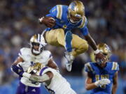 UCLA quarterback Dorian Thompson-Robinson (1) leaps over Washington linebacker Kamren Fabiculanan during the first half of an NCAA college football game Friday, Sept. 30, 2022, in Pasadena, Calif.