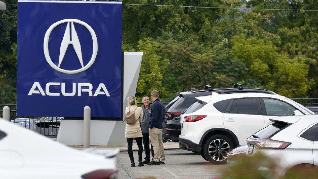 FILE - A salesman talks with customers in an Acura dealership lot in Wexford, Pa., on Sept. 29, 2022. New vehicle sales in the U.S. are expected to have fallen slightly in the third quarter, even with improvement in September. But there are warning signs that consumers' appetite for expensive new cars, trucks and SUVs may be waning. (AP Photo/Gene J.