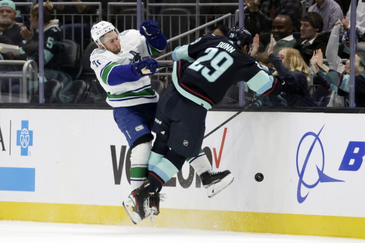 Vancouver Canucks left wing Nils Hoglander (21) collides with Seattle Kraken defenseman Vince Dunn (29) as they battle for the puck during the first period of an NHL hockey game, Thursday, Oct. 27, 2022, in Seattle.