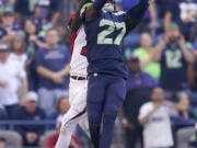 Seattle Seahawks cornerback Tariq Woolen (27) intercepts a pass intended for Arizona Cardinals wide receiver Marquise Brown, rear, during the second half of an NFL football game in Seattle, Sunday, Oct. 16, 2022.