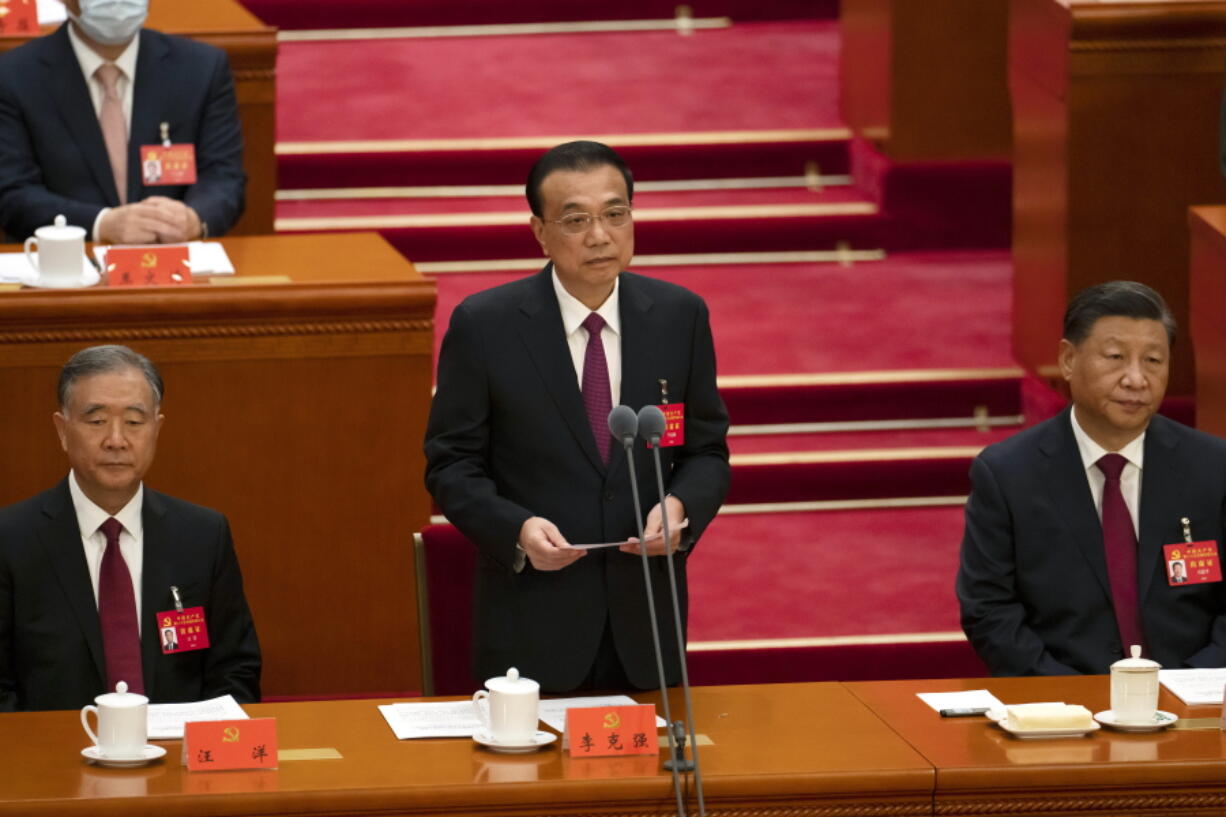 Chinese Premier Li Keqiang is flanked by Politburo Standing Committee member Wang Yang, left, and President Xi Jinping as he speaks during the opening ceremony of the 20th National Congress of China's ruling Communist Party at the Great Hall of the People in Beijing, China, Sunday, Oct. 16, 2022. While Xi is primed to receive a third five-year term as head of China's ruling Communist Party at this week's congress, new members of the party's leading bodies are expected to be appointed at the meeting, whose proceedings are mainly held behind closed doors.