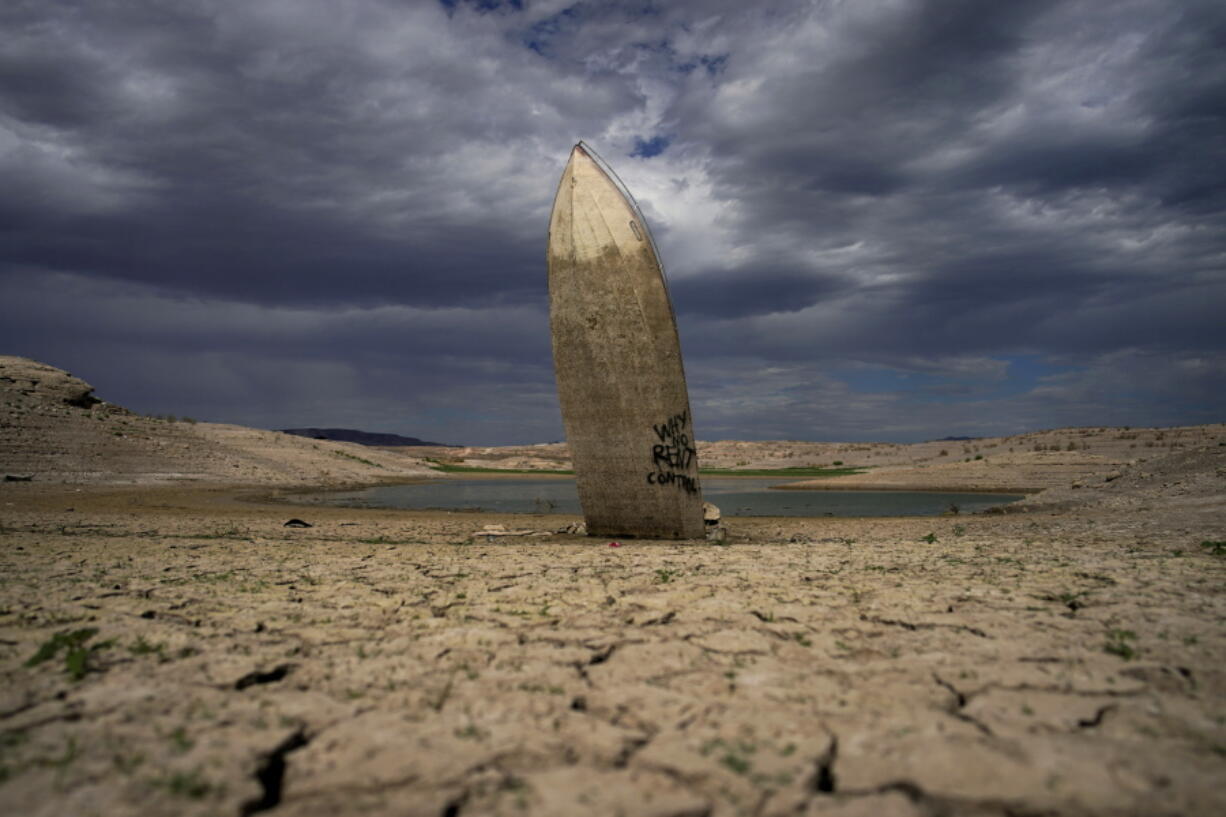 FILE - A formerly sunken boat stands upright into the air with its stern buried in the mud along the shoreline of Lake Mead at the Lake Mead National Recreation Area on June 22, 2022, near Boulder City, Nev. The U.S. Interior Department announced, Friday, Oct. 28, 2022, that it will consider revising a set of guidelines for operating two major dams on the Colorado River in the first sign of what could lead to federal action to protect the shrinking reservoirs behind them.