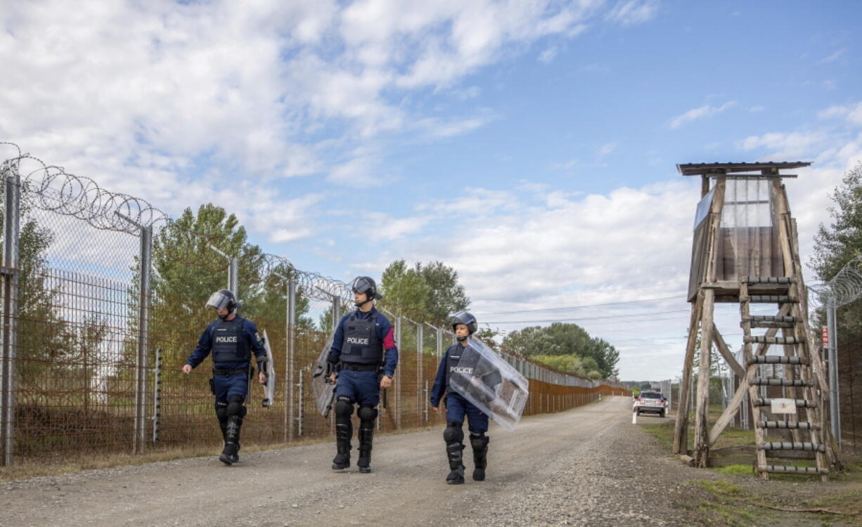 FILE - Operational police officers walk along the service route of Hungary's border with Serbia near Roszke, Southern Hungary, Wednesday, Sept. 28, 2022. The leaders of Hungary, Austria and Serbia met Monday in Budapest to find solutions on how to stem the recently increasing number of migrants arriving in Europe.