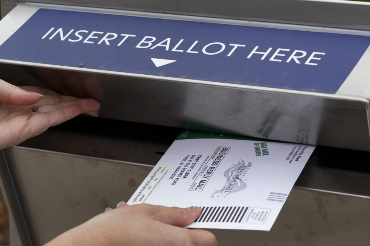 FILE - A Michigan voter inserts her absentee voter ballot into a drop box in Troy, Mich. on Oct. 15, 2020. After the 2020 presidential election, former President Donald Trump and his supporters claimed thousands of votes had been cast fraudulently on behalf of dead voters, even naming specific deceased people whose ballots were supposedly counted. But these claims, which spread in many states including Arizona, Virginia, Nevada, Pennsylvania, Michigan and Georgia, were found to be false.