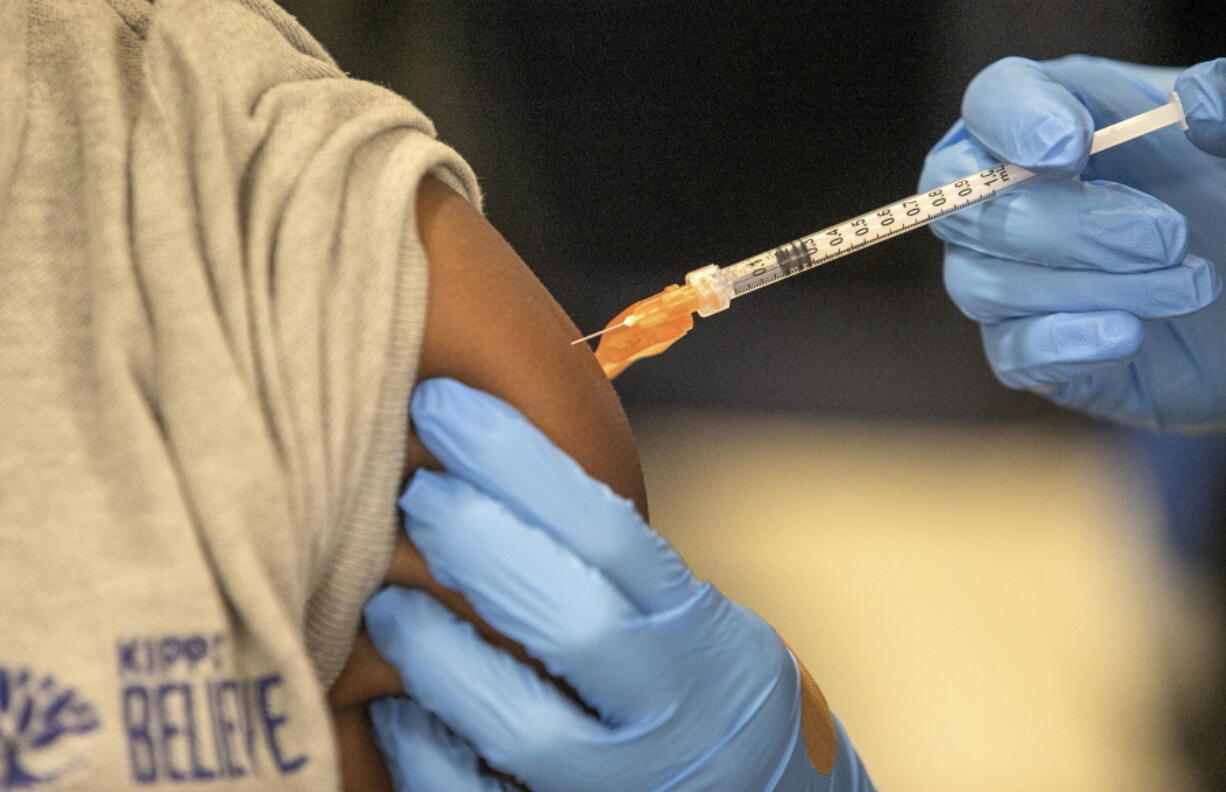 FILE - Medical personnel vaccinate students at a school in New Orleans on Jan. 25, 2022. A Centers for Disease Control and Prevention advisory committee on Thursday, Oct. 20, 2022 voted that the agency should update its recommended immunization schedules to add the COVID-19 vaccine, including to the schedule for children.