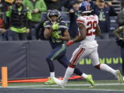 Seattle Seahawks wide receiver Tyler Lockett, left, scores a touchdown past New York Giants safety Xavier McKinney (29) during the second half of an NFL football game in Seattle, Sunday, Oct. 30, 2022.