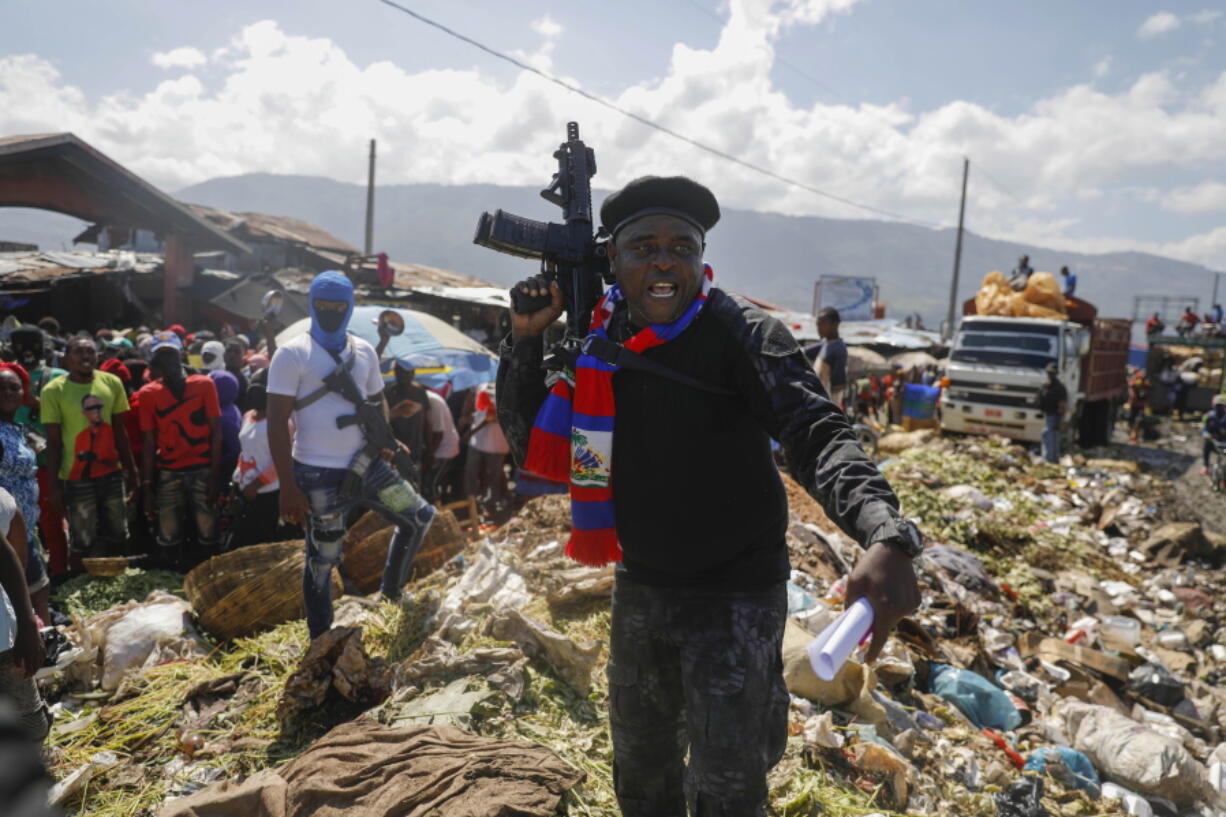 FILE - Barbecue, the leader of the "G9 and Family" gang, stands next to garbage to call attention to the conditions people live in as he leads a march against kidnapping through La Saline neighborhood in Port-au-Prince, Haiti, Friday, Oct. 22, 2021. Haiti Prime Minister Ariel Henry and 18 top-ranking officials have requested on the second week of Oct. 2022, the immediate deployment of foreign armed troops as gangs and protesters paralyze the country.