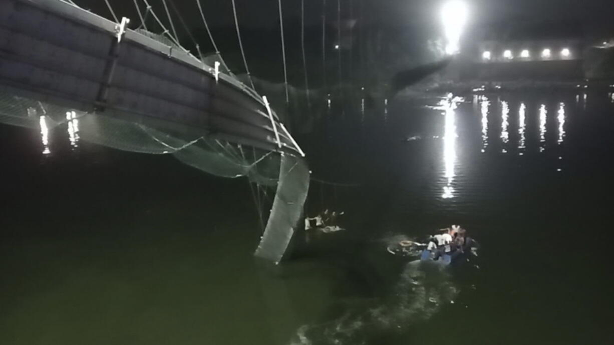 Rescuers on boats search in the Machchu river next to a cable bridge that collapsed in Morbi district, western Gujarat state, India, Sunday, Oct.30, 2022. Dozens are feared dead and several are injured in the accident.