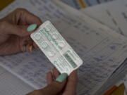 FILE - A woman shows a pack with iodine tablets before distributing them to residents at a local school in case of a radiation leak in Zaporizhzhia, Ukraine, Friday, Sept. 2, 2022. The war in Ukraine has heightened fears about nuclear exposure -- and interest in iodine pills that can help protect the body from some radiation.