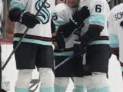 Seattle Kraken center Karson Kuhlman, center, is congratulated, after scoring the go-ahead goal against the Colorado Avalanche, by defensemen Jamie Oleksiak, left, and Adam Larsson during the third period of an NHL hockey game Friday, Oct. 21, 2022, in Denver.