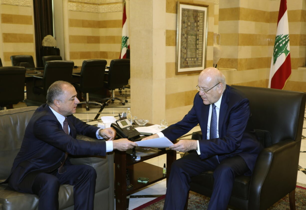 In this photo released by Lebanon's official government photographer Dalati Nohra, Lebanese Prime Minister Najib Makati, right, receives the final draft of the maritime border agreement between Lebanon and Israel from his deputy Elias Bou Saab who leads the Lebanese negotiating team, in Beirut, Lebanon, Tuesday, Oct. 11, 2022. Israel's prime minister said Tuesday that the country has reached an "historic agreement" with neighboring Lebanon over their shared maritime border after months of U.S.-brokered negotiations.