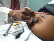 FILE - A doctor uses a hand-held Doppler probe on a pregnant woman to measure the heartbeat of the fetus on Dec. 17, 2021, in Jackson, Miss. COVID-19 drove a dramatic increase in the number of women who died from pregnancy or childbirth complications in the U.S. last year, a crisis that has disproportionately claimed Black and Hispanic women as victims, according to a report released Wednesday, Oct. 19, 2022. (AP Photo/Rogelio V.