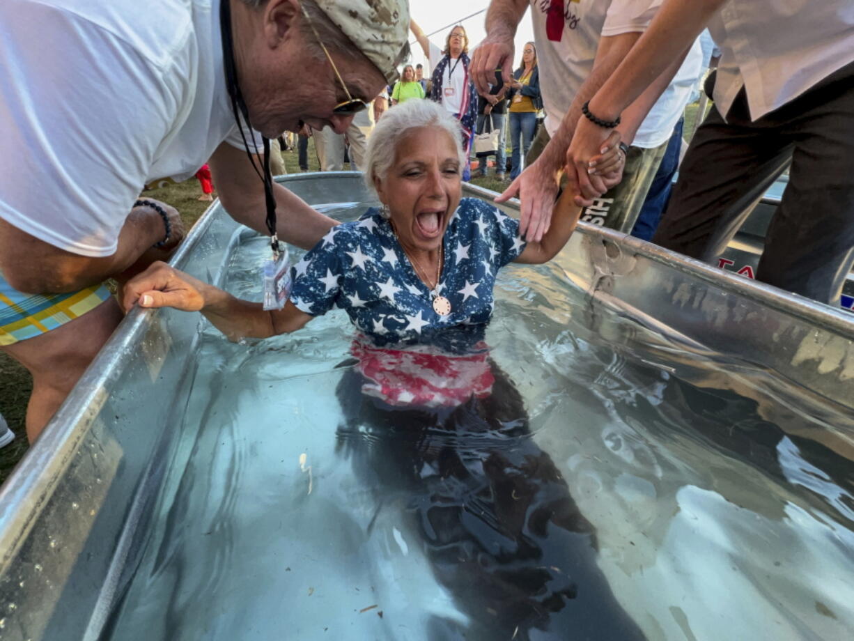 A woman is baptized during the ReAwaken America Tour at Cornerstone Church in Batavia, N.Y., Friday, Aug. 12, 2022. In the version of America laid out at the ReAwaken tour, Christianity is at the center of American life and institutions, it's under attack, and attendees need to fight to restore and protect the nation's Christian roots. It's a message repeated over and over at ReAwaken -- one that upends the constitutional ideal of a pluralist democracy.