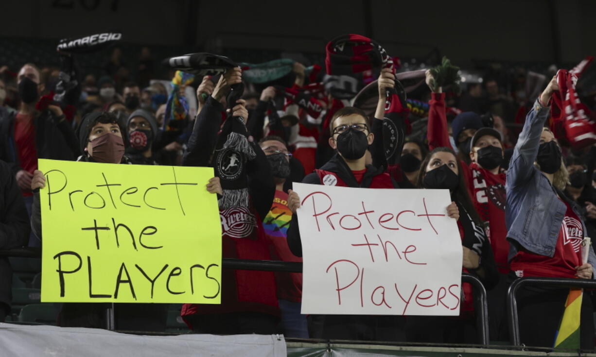 FILE - Portland Thorns fans hold signs during the first half of the team's NWSL soccer match against the Houston Dash in Portland, Ore., Wednesday, Oct. 6, 2021. An independent investigation into the scandals that erupted in the National Women's Soccer League last season found emotional abuse and sexual misconduct were systemic in the sport, impacting multiple teams, coaches and players, according to a report released Monday, Oct. 3, 2022.