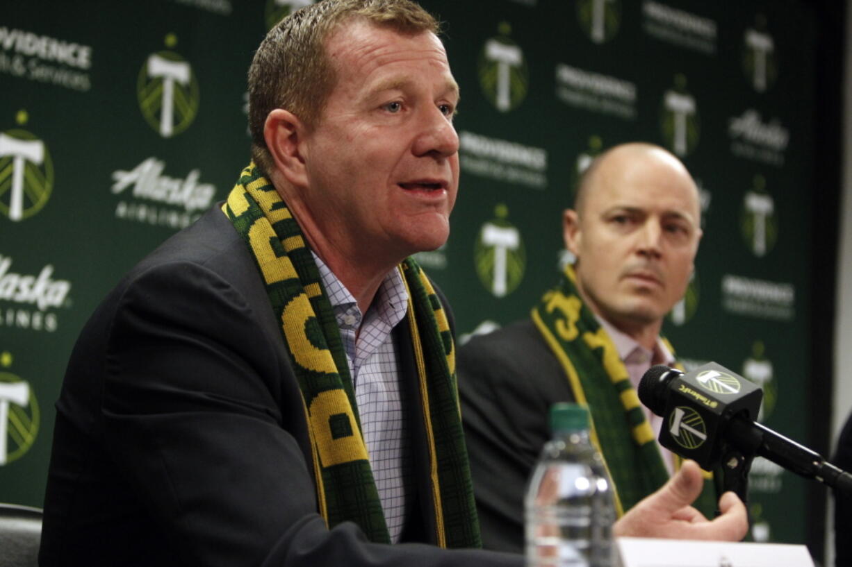 FILE - Portland Timbers team president and general manager Gavin Wilkinson, left, speaks as team owner Merritt Paulson, right, listens during an MLS soccer news conference on Jan. 8, 2018, in Portland, Ore. Wilkinson and Paulson have been removed from any decision-making roles with the Portland Thorn's National Women's Soccer League club until the findings are released from an ongoing investigation into numerous scandals around the league.