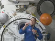 In this image from video made available by NASA, astronaut Nicole Mann shows her dreamcatcher during an interview on Wednesday, Oct. 19, 2022. The first Native American woman in space said Wednesday that she's overwhelmed by the beauty and delicacy of Mother Earth, and is channeling "positive energy" as her five-month mission gets underway.