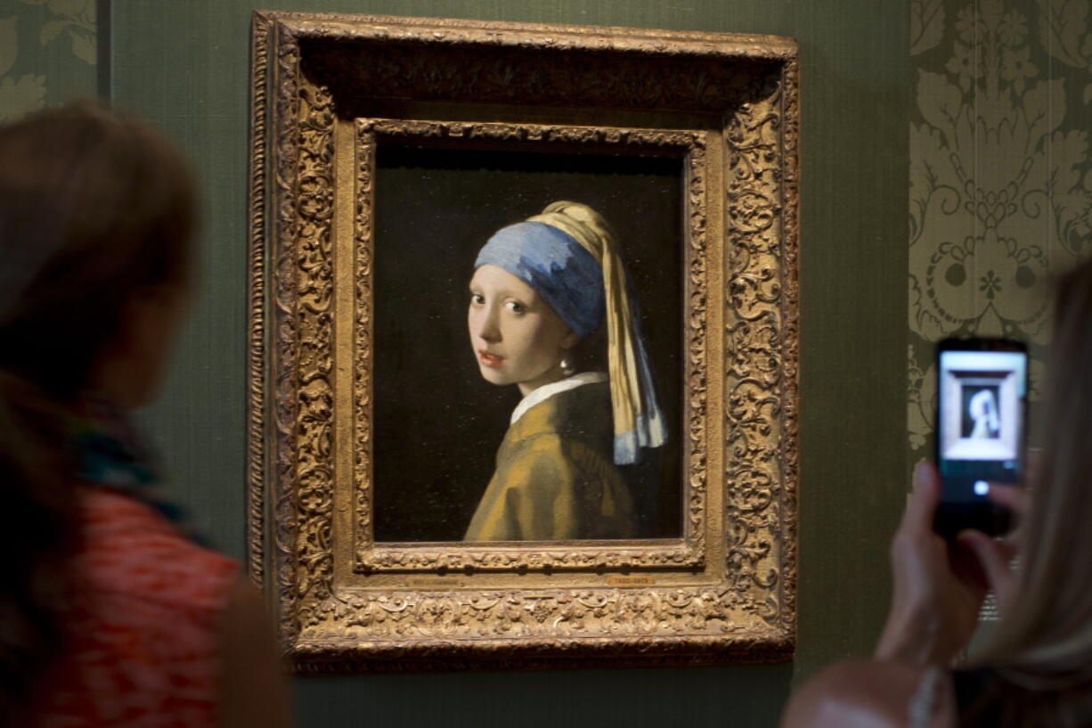 FILE- Visitors take pictures of Johannes Vermeer's Girl with a Pearl Earring (approx. 1665) during a preview for the press of the renovated Mauritshuis in The Hague, Netherlands, June 20, 2014. The Vermeer masterpiece "Girl with a Pearl Earring" has become the latest artwork targetted by climate activists in a protest at the Mauritshuis museum in The Hague on Thursday, Oct. 27, 2022. The museum did not immediately return calls and emails for comment after a video of the protest was posted on Twitter.