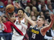 Portland Trail Blazers guard Anfernee Simons, left, shoots over Denver Nuggets center Nikola Jokic during the second half of an NBA basketball game in Portland, Ore., Monday, Oct. 24, 2022.