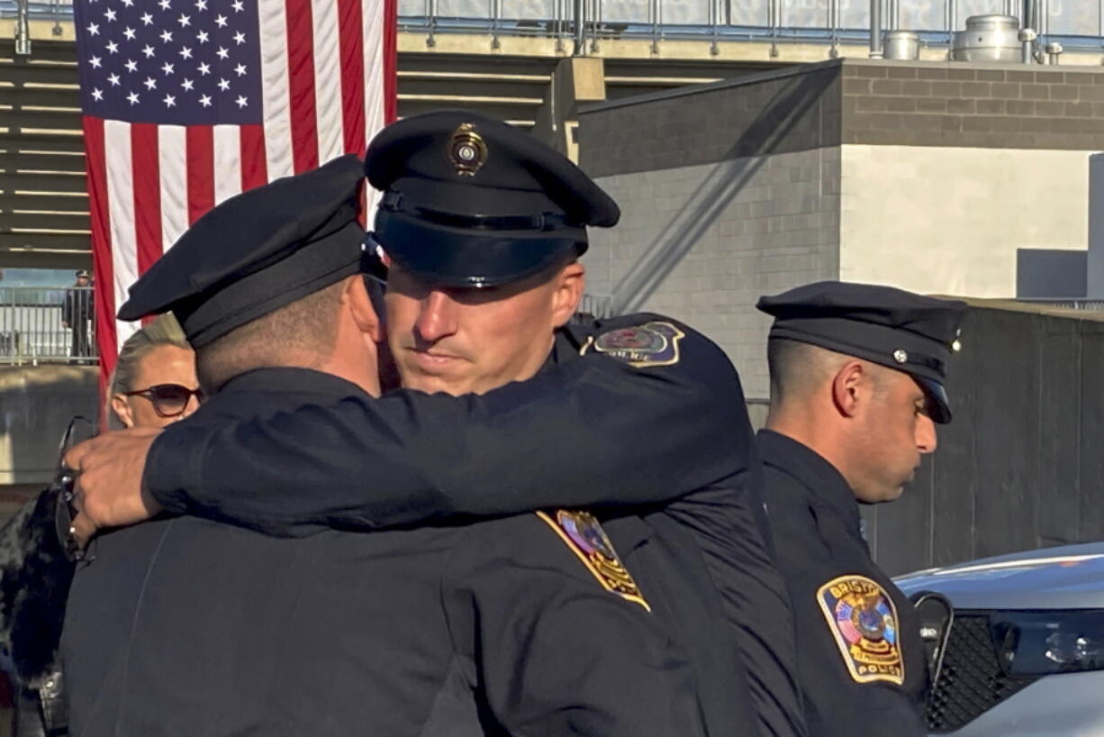 Two Bristol Police department officers hug before a joint police funeral, Friday, Oct. 21, 2022, in East Hartford, Conn. Thousands of police officers from around the country have gathered in a football stadium in Connecticut for a joint funeral for Bristol officers Dustin DeMonte and Alex Hamzy who were shot to death in an apparent ambush on Oct. 12.