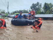 In this photo provided by the Philippine Coast Guard, rescuers use boats to evacuate residents from flooded areas due to Tropical Storm Nalgae at Parang, Maguindanao province, southern Philippines on Friday Oct. 28, 2022. Floodwaters rapidly rose in many low-lying villages, forcing some villagers to climb to their roofs, where they were rescued by army troops, police and volunteers, officials said.