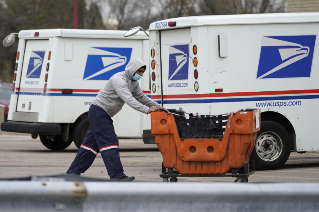 FILE - A U.S. Postal Service employee works outside a post office in Wheeling, Ill., Dec. 3, 2021. A federal judge has set limits on one of the U.S. Postal Service's cost-cutting practices that contributed to a worrisome slowdown of mail deliveries ahead of the 2020 presidential election. (AP Photo/Nam Y.