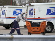 FILE - A U.S. Postal Service employee works outside a post office in Wheeling, Ill., Dec. 3, 2021. A federal judge has set limits on one of the U.S. Postal Service's cost-cutting practices that contributed to a worrisome slowdown of mail deliveries ahead of the 2020 presidential election. (AP Photo/Nam Y.