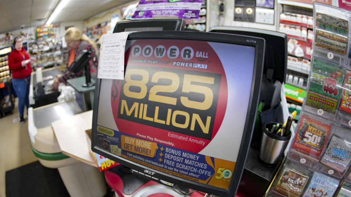 Customers pay for their groceries next to the lottery ticket display showing the jackpot amount for the Saturday, Oct. 29, drawing of the Powerball lottery at a market in Prospect, Pa., Friday, Oct. 28, 2022. Saturday's jackpot projected winnings of an estimated $825 million is the fifth-highest in U.S. history.