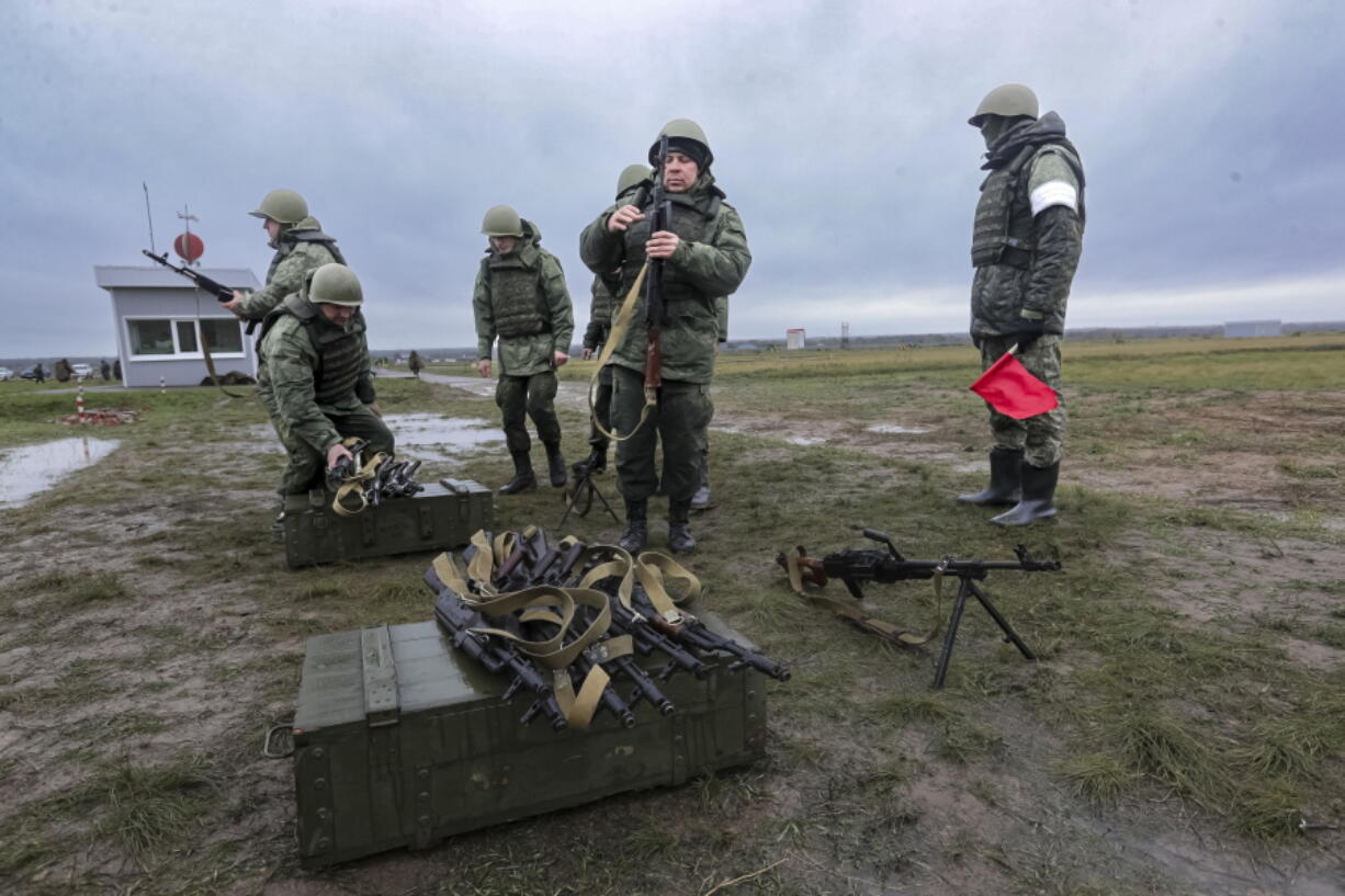 Recruits prepare their weapons as an instructor looks at them during a military training at a firing range in Volgograd region, Russia, Thursday, Oct. 27, 2022.
