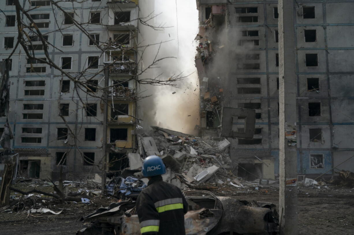 A firefighter looks at a part of a wall falling from the residential building that was heavily damaged after a Russian attack in Zaporizhzhia, Ukraine, Sunday, Oct. 9, 2022.