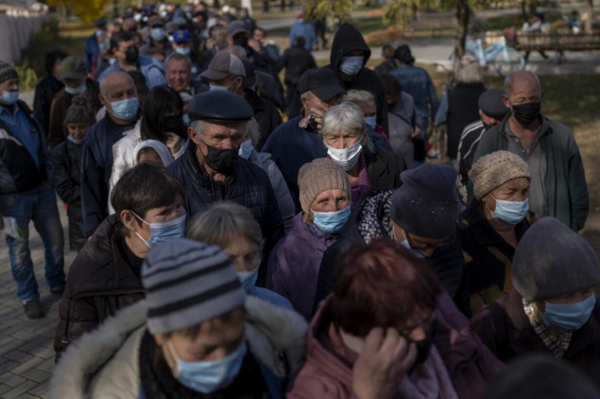 People queue up to wait a ration food from World Central Kitchen organisation in the center of Mykolaiv, Monday, Oct. 24, 2022. As Ukraine crosses the mark of eight months anniversary since the start of full-scale war, the residents of southern Mykolaiv, who suffer shelling almost every night, are determined to fight as long as it takes to liberate all the regions.