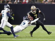 New Orleans Saints' Taysom Hill (7) carries the ball as Seattle Seahawks cornerback Tre Brown tries to make the tackle during an NFL football game in New Orleans, Sunday, Oct. 9, 2022.