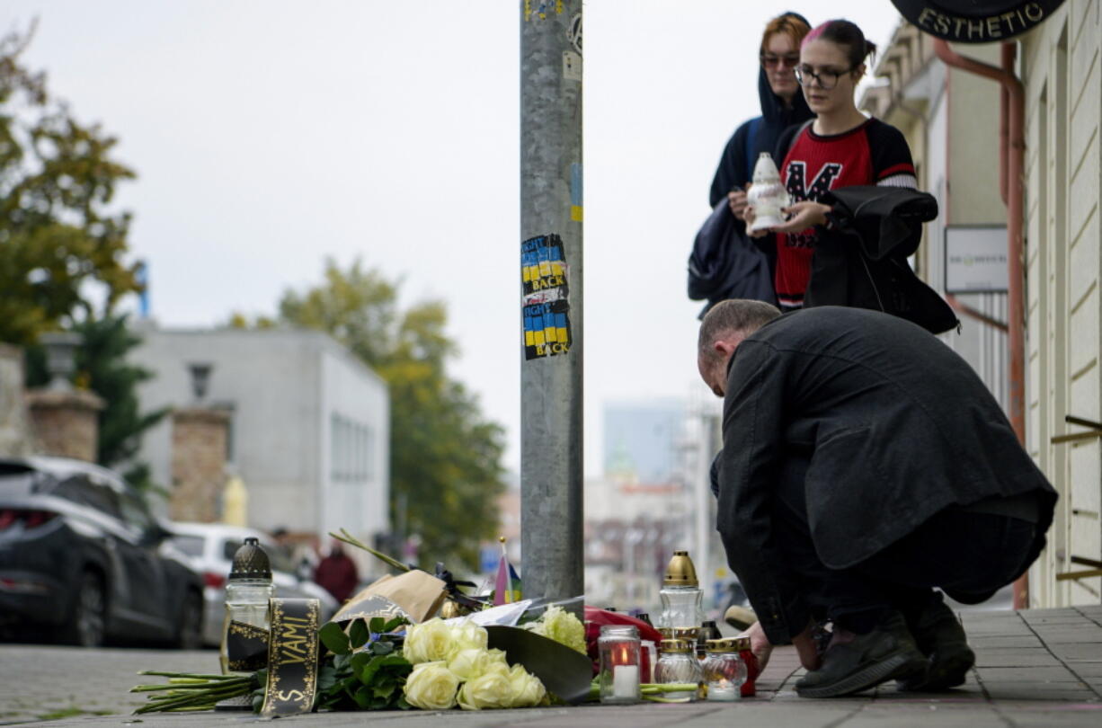 People lay flowers and light candles at the scene of Wednesday's attack on Zamocka Street in Bratislava, Slovakia, Thursday, Oct. 13, 2022. Slovakia's police say they found the body of a suspect who allegedly fatally shot two people the previous day in the capital in what some officials are suggesting was a hate crime. Two men were killed and a woman was wounded on Wednesday evening near or at a bar which is a popular spot for the local LGBTQ community in downtown Bratislava.